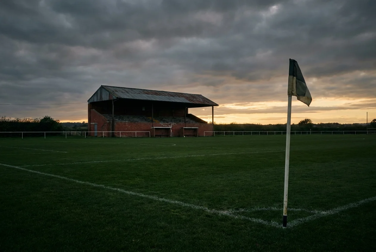 Illustrative empty football ground at dusk, with a corner flag in the foreground